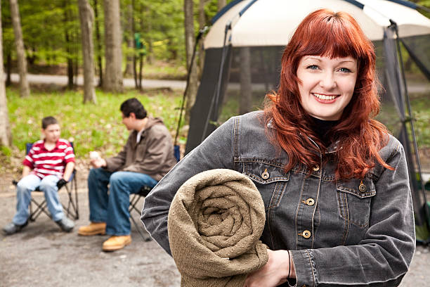 Happy mature couple communicating while standing embraced on camping in the forest. Copy space.