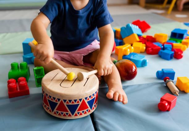 kleiner junge mit spaß und spielen holzspielzeug trommel - musikinstrument stock-fotos und bilder