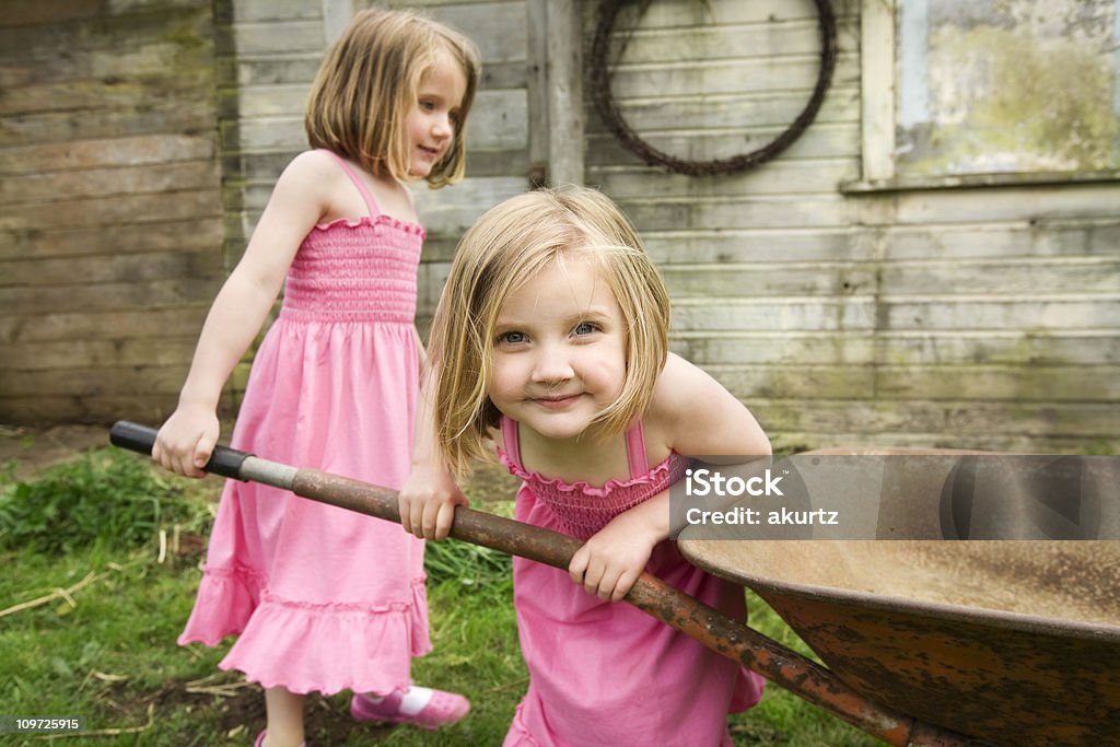 Duas meninas tocando do lado de fora, com carrinho de mão sisters - Foto de stock de Amizade royalty-free