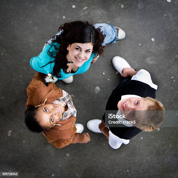 Three Friends Standing In A Circle Looking Up And Smiling Stock Photo - Download Image Now