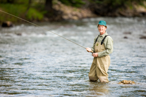 Hombre maduro pesca con mosca en el río de montaña photo