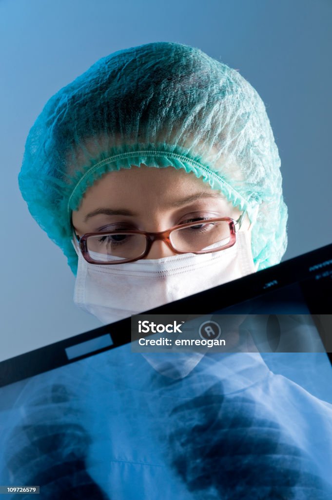Doctora usando una máscara mirando a rayos X - Foto de stock de Adulto libre de derechos