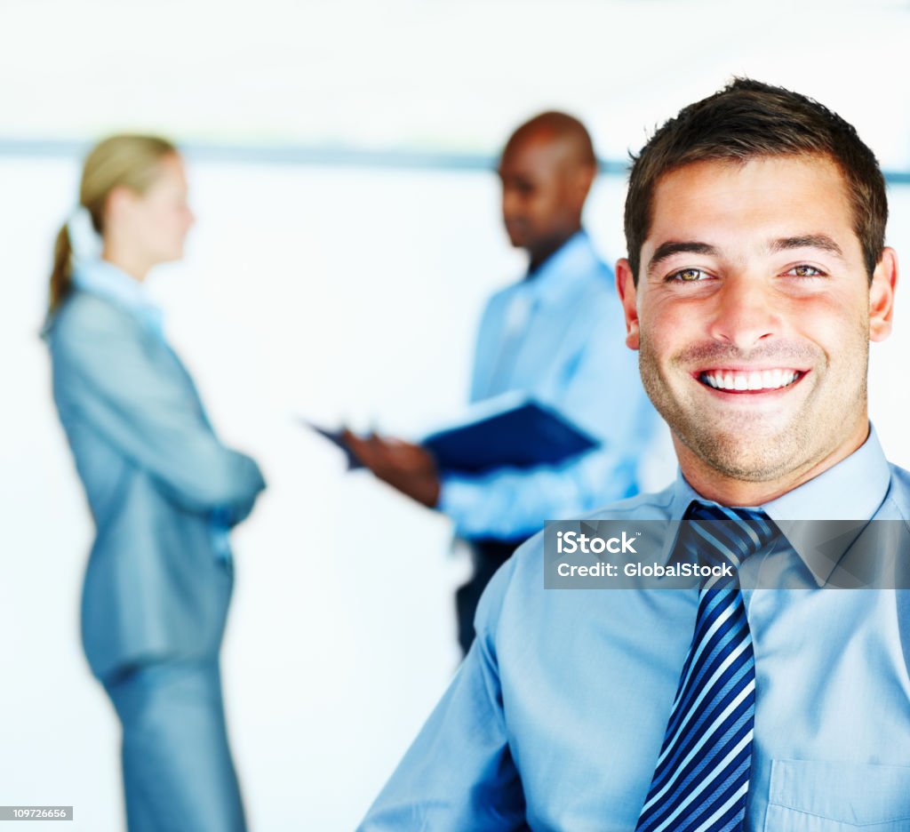 Empresário sorridente com colegas no fundo - Royalty-free Adulto Foto de stock