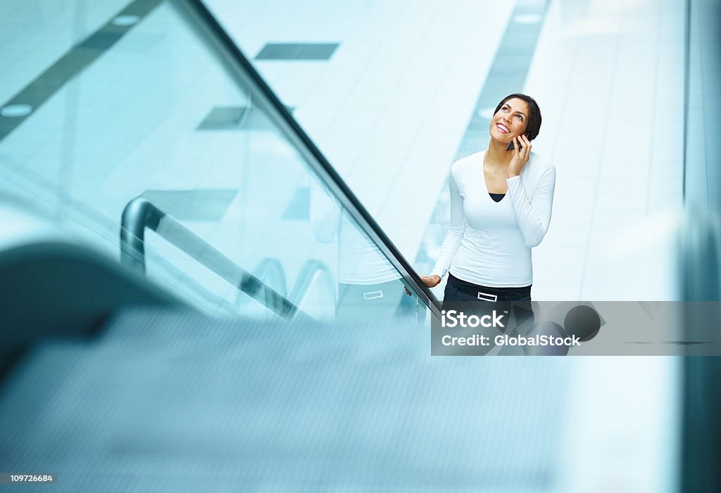 Jovem mulher em pé na Escada Rolante e utilizar cellphone - Royalty-free 20-24 Anos Foto de stock