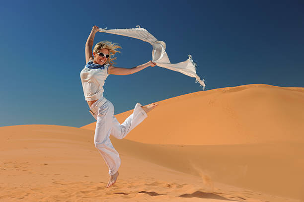 Young woman jumping with happiness on the dunes.