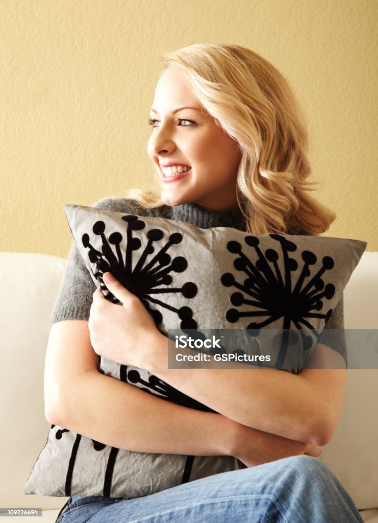 Loira jovem mulher abraçando e almofada sobre um sofá - Foto de stock de Travesseiro royalty-free