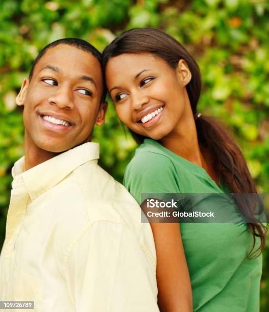 Foto de Jovem Casal De Pé Atrás De Si E Sorrindo e mais fotos de stock de Costas Com Costas - Costas Com Costas, Primeiro plano, 20 Anos