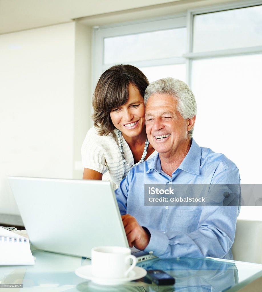 Casal maduro usando o laptop em casa e sorrindo - Foto de stock de 50-54 anos royalty-free
