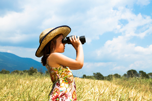 Child with binoculars in a wheat field