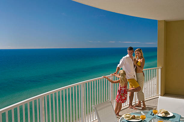 Family of Three On Hotel Balcony Overlooking Ocean Mom, dad and daughter standing on the balcony overlooking Gulf of Mexico. gulf of mexico photos stock pictures, royalty-free photos & images