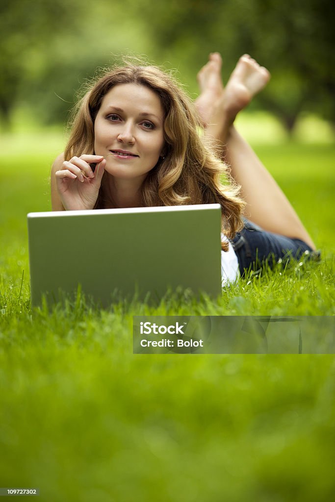 Młoda kobieta za pomocą laptopa w parku - Zbiór zdjęć royalty-free (Brązowe włosy)