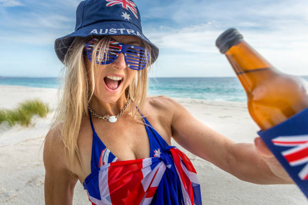 Aussie beach barbeque party.  aussie culture outdoor lifestyle Happy patriotic woman on the beach holding a cold beer or other beverage.  Australian culture, beach party, outdoor lifestyle, vacations, Australia day celebration larrikin stock pictures, royalty-free photos & images
