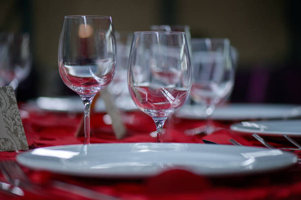 istock Fine dining table setting with white china and wine and water crystal glasses, with silverware in the order of use, and romantic red tablecloth 1097274970