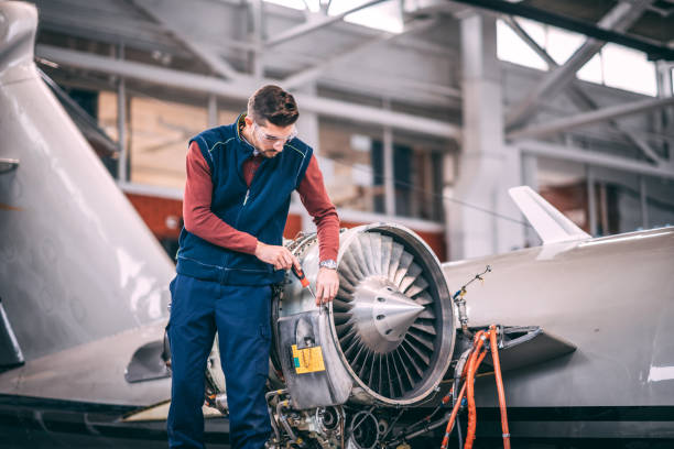 istock Aircraft mechanic using a screwdriver to open up a panel on a jet engine of a small aircraft in a maintenance hangar 1097276278