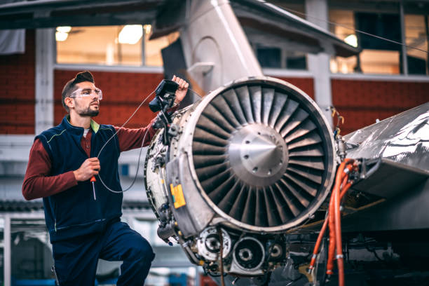istock Aircraft engineer in a hangar holding a camera probe while repairing and maintaining airplane jet engine 1097276324