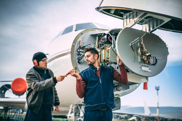 istock Two aircraft mechanics working on a radar array under the opened up nose cone of a private airplane parked on an airport field 1097278854