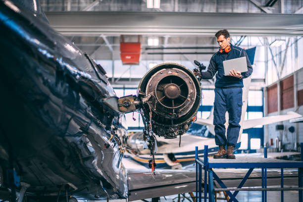 istock Aircraft engineer holding a laptop and diagnosing a jet engine of a small airplane while standing on a raised platform in a hangar 1097282196