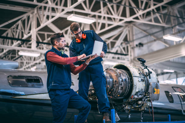 istock Aircraft mechanics working together on a laptop in a hangar next to a opened up jet engine 1097283384