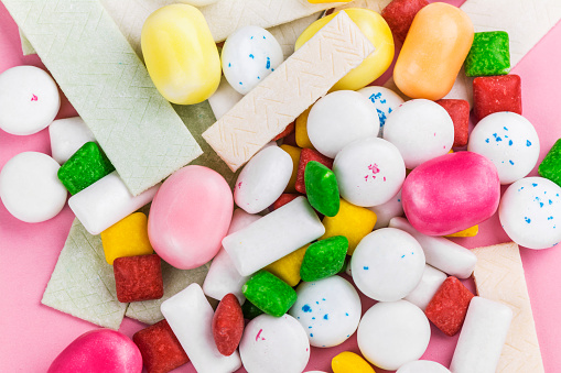 Assortment of bubble gum on pink background. Copy space