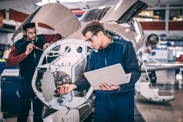 istock Two aircraft mechanics using a laptop and hand tools to work on the framing and a sensor and radar array of an airplane 1097287474
