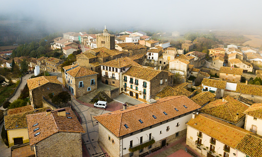 View from drone of roofs of houses in traditional village of Liedena in foggy morning, Navarre, Spain