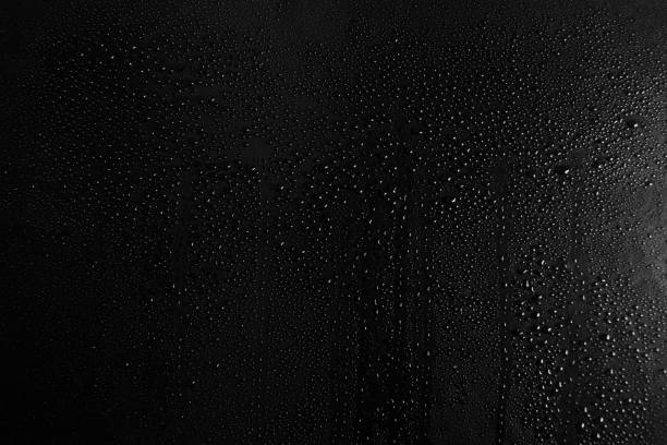 istock Drops of water on a dark glass texture background 1097293340