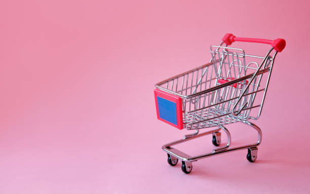 istock Shopping trolley on soft pink pastel background with copy space. 1097296258