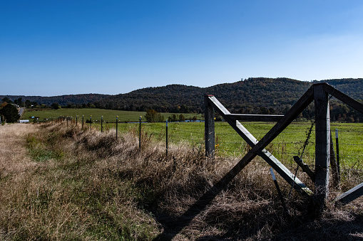 Fencing corner brace with barbed wire fencing and metal posts set against an Appalachian countryside background.