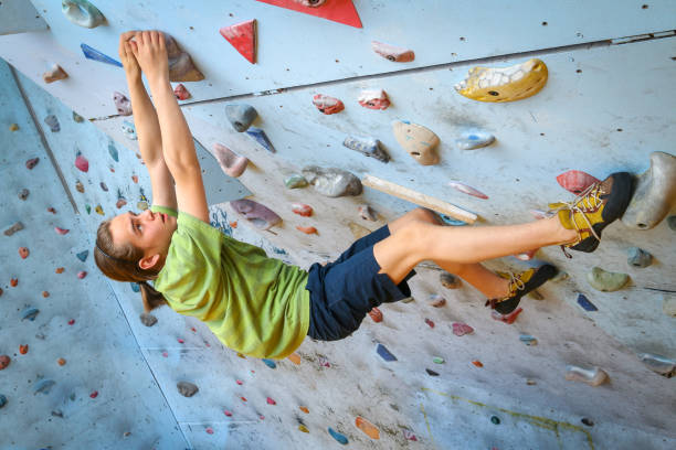 adolescente formação escalada na parede de escalada indoor - climbing wall rock climbing holding reaching - fotografias e filmes do acervo