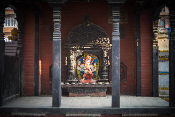 Sunlight obliquely strikes the elephant head of the god Ganesh in a covered shrine