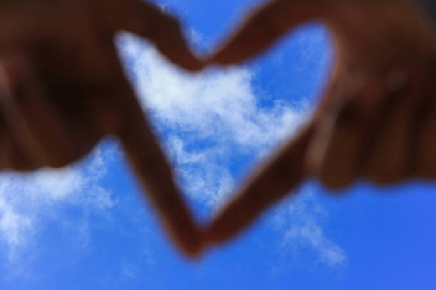 hands making a heart shape with blur blue sky. Love concept