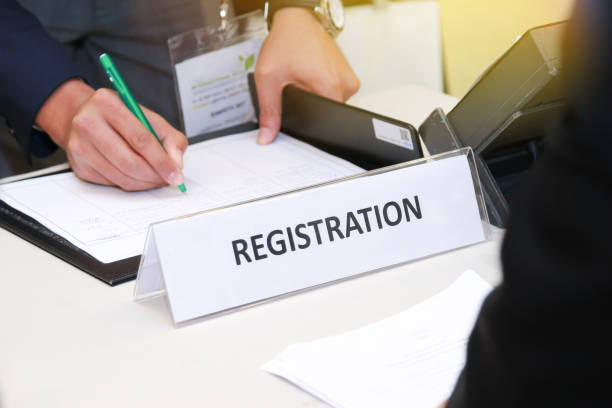 primer plano de la mesa de inscripción frente a centro de conferencias con la escritura del hombre de negocios sobre la mesa - voter registration fotografías e imágenes de stock