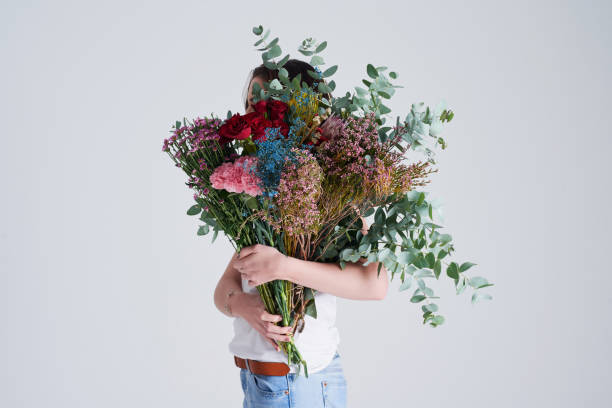 Do you suppose she’s a wildflower? Studio shot of an unrecognizable woman covering her face with flowers against a grey background bunch of flowers stock pictures, royalty-free photos & images