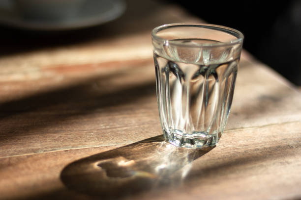 シャドウ、朝の日差しの木製テーブルの上のガラスの水します。 - glass cup ストックフォトと画像