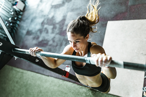 High angle view of determined female athlete exercising chin-ups during cross training in a health club.
