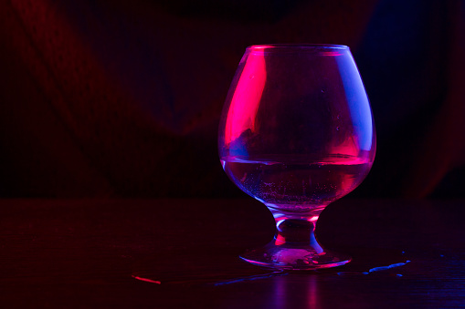 glass with alcohol in neon light in a bar or club