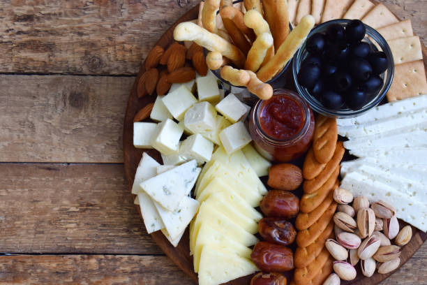 istock Cheese plates served with grissini, crackers, dates, jam, olives and nuts on wooden background. Cheese board. Snack to wine 1097322152