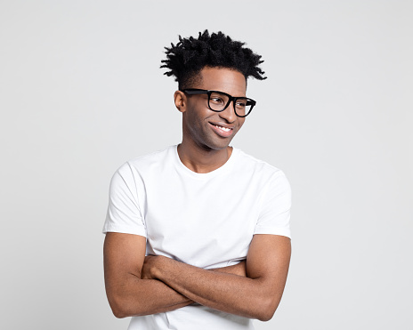 Portrait of happy afro american guy with nerd eyeglasses. Man wearing white t-shirt looking away with arms crossed.