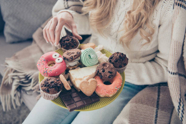 vista ravvicinata ritagliata della signora dai capelli ondulati che tiene in mano un grande piatto di allettanti dolci domestici fatti in casa diversi che si godono in casa - large group of objects foto e immagini stock