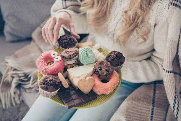 Photo of Cropped close-up view of wavy-haired lady holding in hands large big plate of tempting seductive homemade domestic different sweets enjoying in house