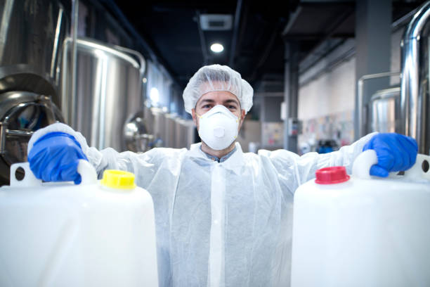 istock Industrial worker with protective mask and white uniform holding plastic cans for chemical industry. 1097333514