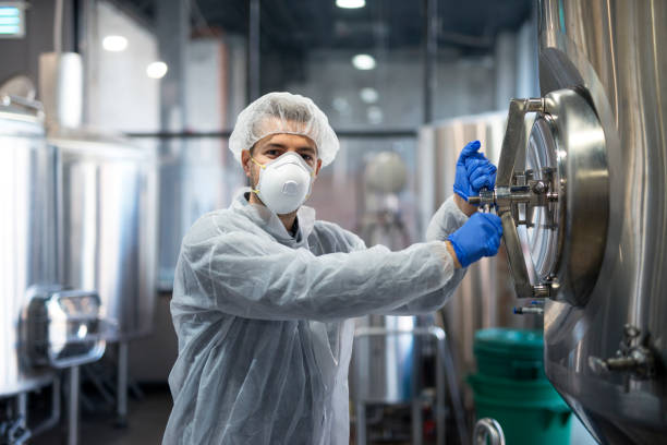 istock Technologist industrial worker opening processing tank in factory production line. Worker wearing protective mask white uniform and hairnet. 1097336516