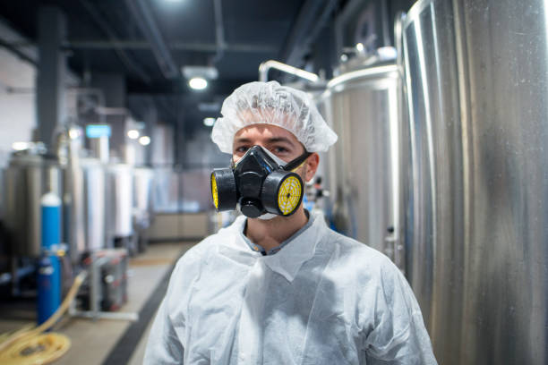 retrato do trabalhador industrial vestindo uniforme de proteção e máscara de gás. tecnólogo em linha de produção industrial. - hazardous materials protection - fotografias e filmes do acervo