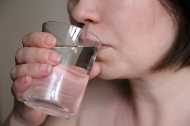 istock Woman drinking clean water from a glass close-up, selective focus 1097340496