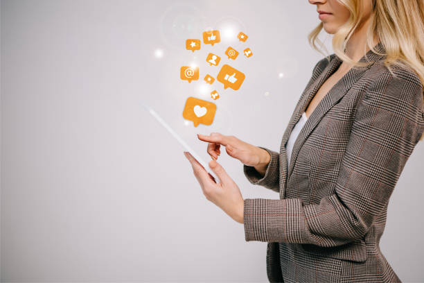 cropped view on businesswoman in suit touching digital tablet with multimedia icons isolated on grey - mobility working digital tablet people imagens e fotografias de stock