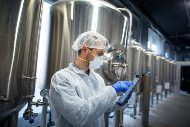 istock Technologist in protective suit holding tablet and checking production in factory plant. Industrial worker wearing protection mask hairnet and gloves. 1097346980