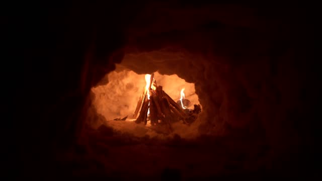 A cozy bonfire burning inside of an igloo