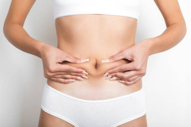 woman pinching her stomach on white background - overweight women body abdomen imagens e fotografias de stock