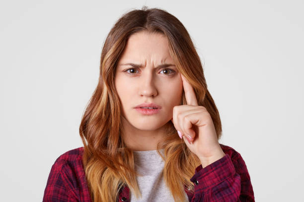 istock Headshot of thoughtful bothered woman with serious expression keeps index finger on temple, tries to focuse on something, wears elegant clothes, isolated over white background. Pensive lady. 1097360894