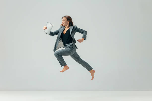 mujer de negocios feliz bailando y sonriente aisladas en blanco. - jumping women running vitality fotografías e imágenes de stock